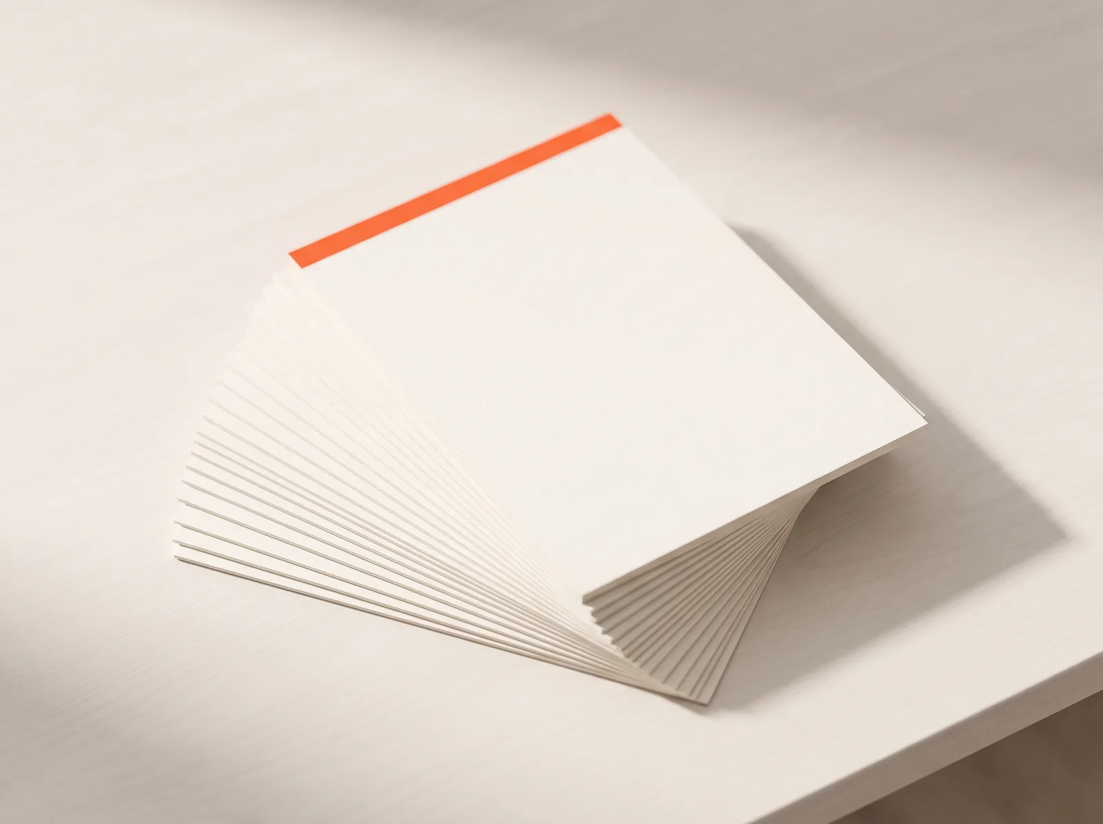 A stack of blank sheets of paper, the top one with an orange edge